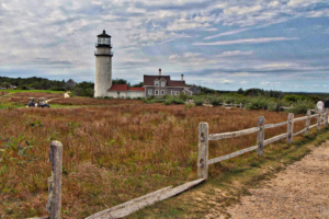 Cape Cod Highland Lighthouse in Truro, MA with clear blue sky and grassy foreground