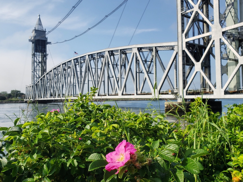 The Cape Cod Canal Railroad Bridge lowered over the canal with a sunset sky in the background