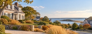 Shingled Cape Cod homes with stone walls overlooking a calm bay in early fall